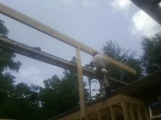 Carpenter setting a ridge beam over a new addition frame — Ice Dam Removal by Roofing Brothers in Ford