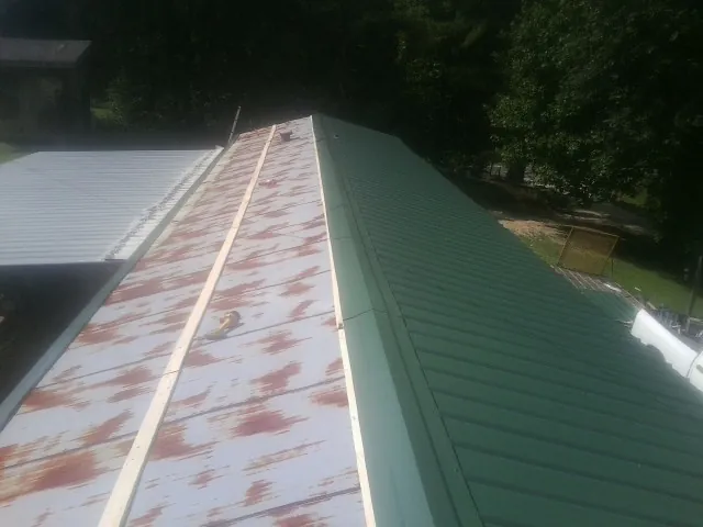Old rusted panels beside newly installed green metal roofing — Wind Damage Roof Repair by Roofing Brothers in Ford